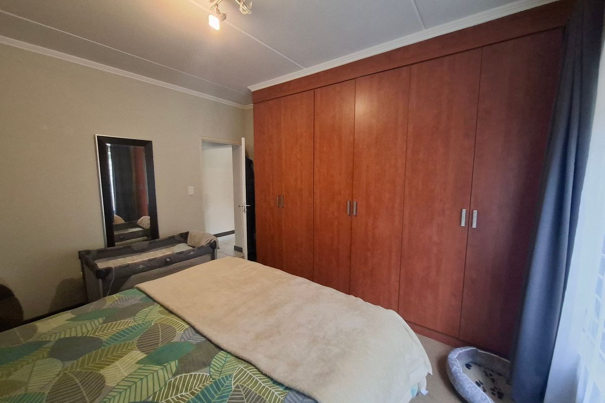 A bedroom featuring extensive floor-to-ceiling built-in wooden cupboards, neutral wall finishes, and a central ceiling light fixture.