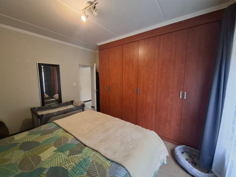 A bedroom featuring extensive floor-to-ceiling built-in wooden cupboards, neutral wall finishes, and a central ceiling light fixture.