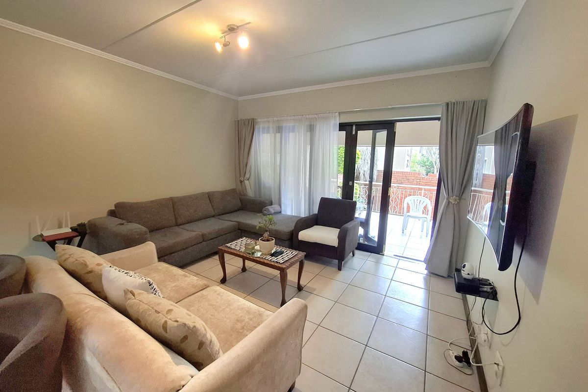 A comfortable living room featuring tiled flooring and a sliding glass door that provides access to an outdoor patio area.