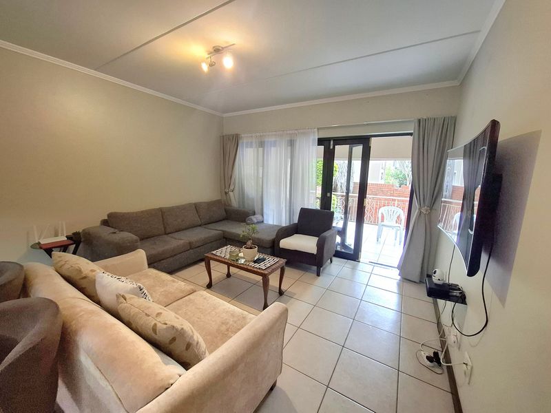A comfortable living room featuring tiled flooring and a sliding glass door that provides access to an outdoor patio area.
