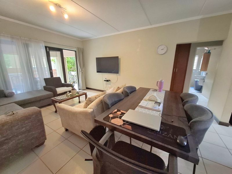 An open-plan living and dining area featuring tiled flooring, neutral walls, and a sliding glass door leading to an outdoor space.