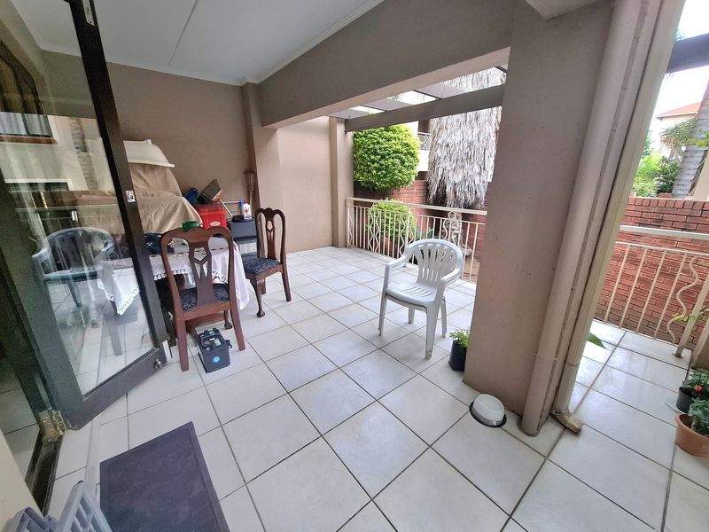 A covered balcony featuring tiled flooring and a metal balustrade, providing an outdoor space accessible through a sliding glass door.