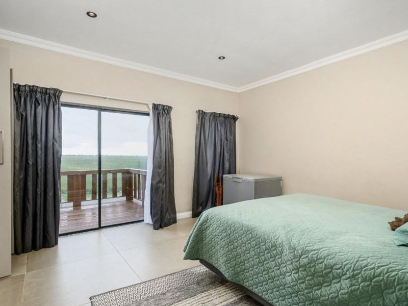 Spacious bedroom featuring neutral tiled flooring, built-in wardrobe, and sliding glass doors providing direct access to an outdoor balcony with scenic views.