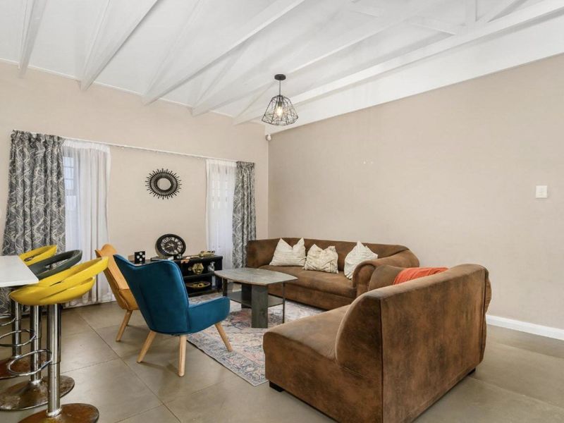 Spacious open-plan living area featuring high exposed beam ceilings, tiled flooring, and a functional kitchen island, creating a bright and airy atmosphere.