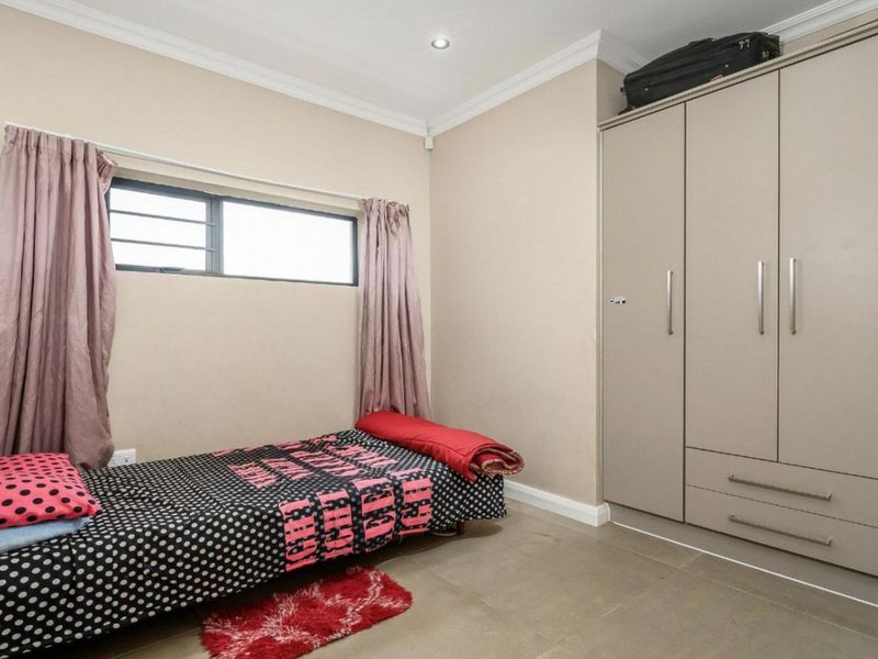 A well-maintained bedroom featuring neutral wall tones, tiled flooring, and ample built-in cupboard storage space.