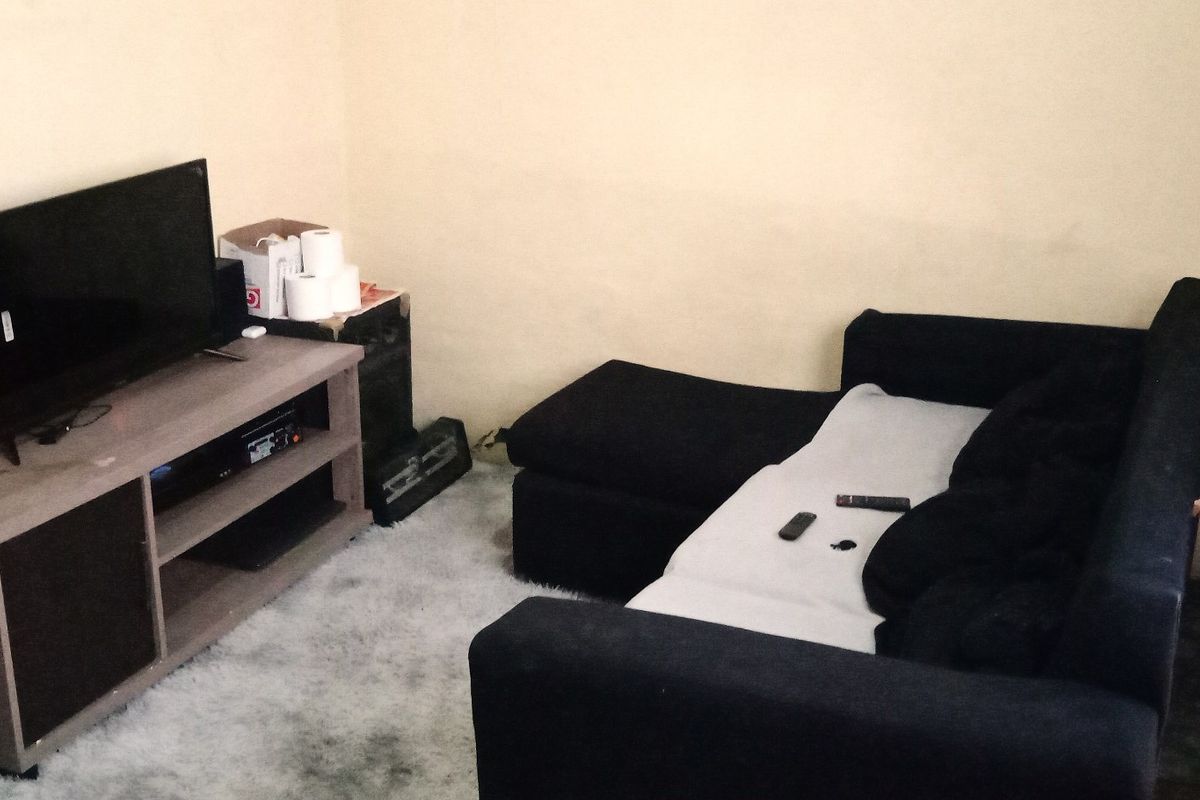 A small living room area featuring plain walls and basic flooring, suitable for a cozy seating arrangement.