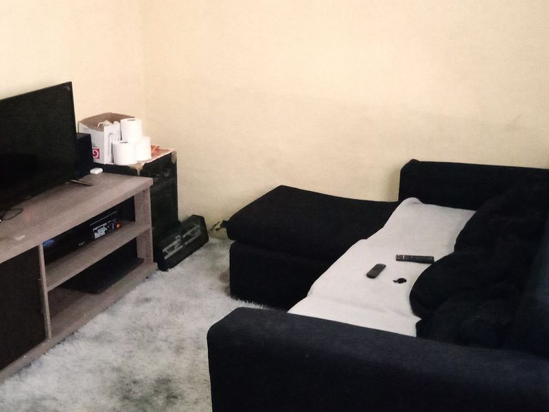 A small living room area featuring plain walls and basic flooring, suitable for a cozy seating arrangement.