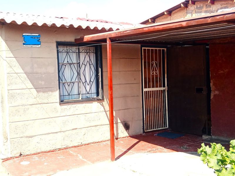 Front exterior view of a house featuring a covered patio area, security gate, and security bars on the windows.