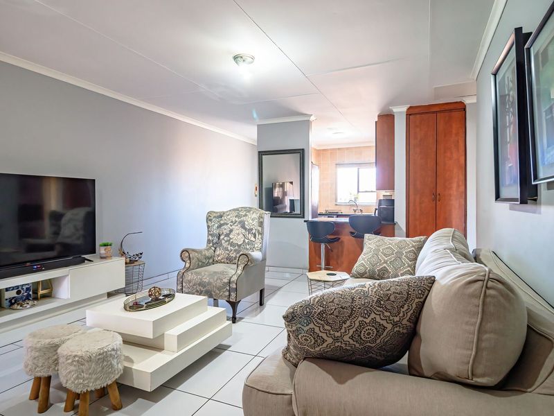 Open-plan living area featuring tiled flooring and a functional kitchen with a breakfast bar and built-in cabinetry.