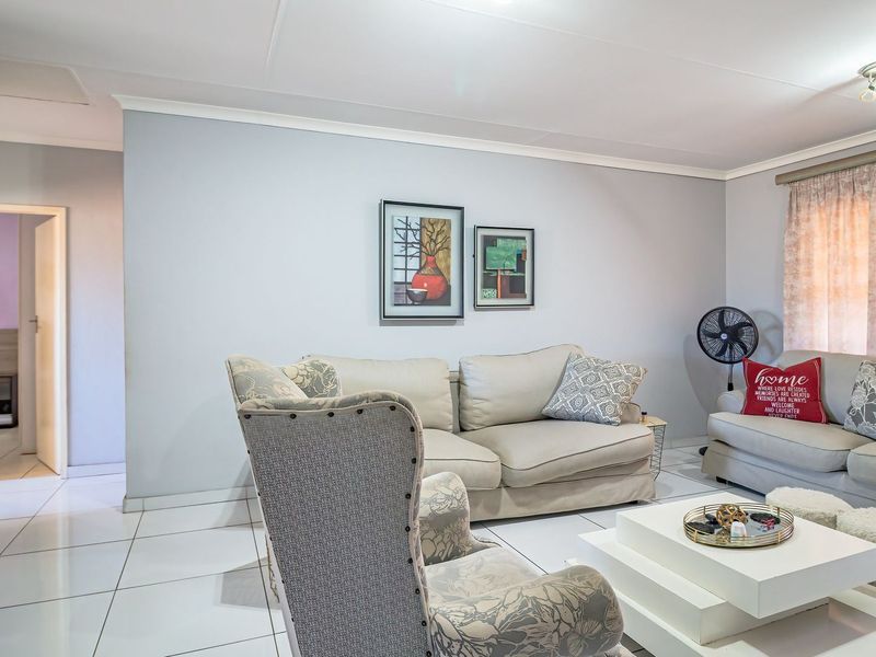 A well-maintained living room featuring neutral tiled flooring, light grey walls, and a built-in cupboard, offering a clean and functional living space.