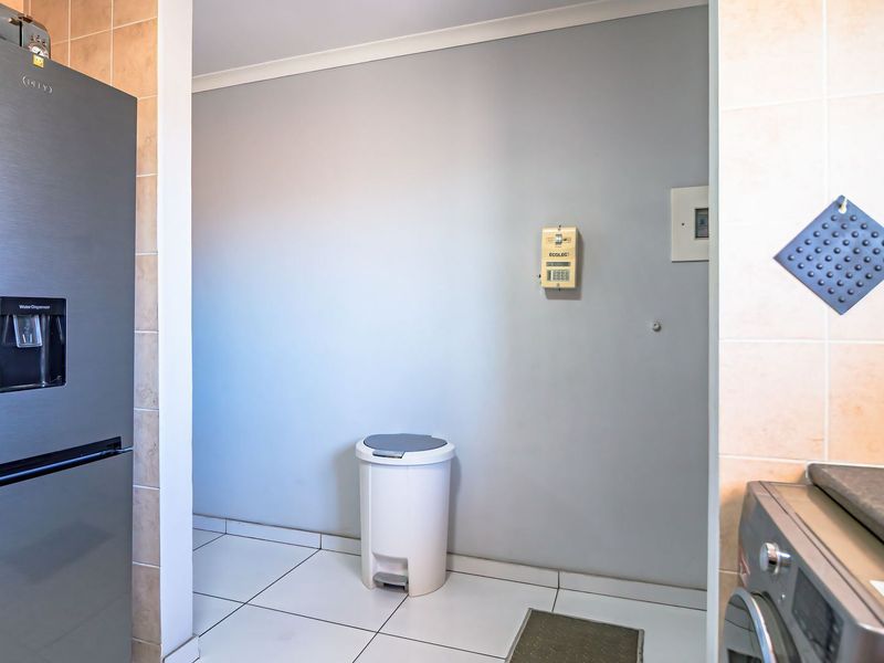 A functional scullery or utility area featuring tiled flooring, wall tiling, and integrated security and electrical infrastructure.