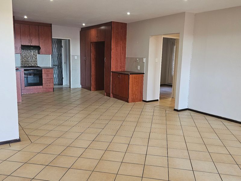 Spacious open-plan living area featuring tiled flooring, recessed lighting, and a functional kitchen with built-in cabinetry, oven, and extractor fan.