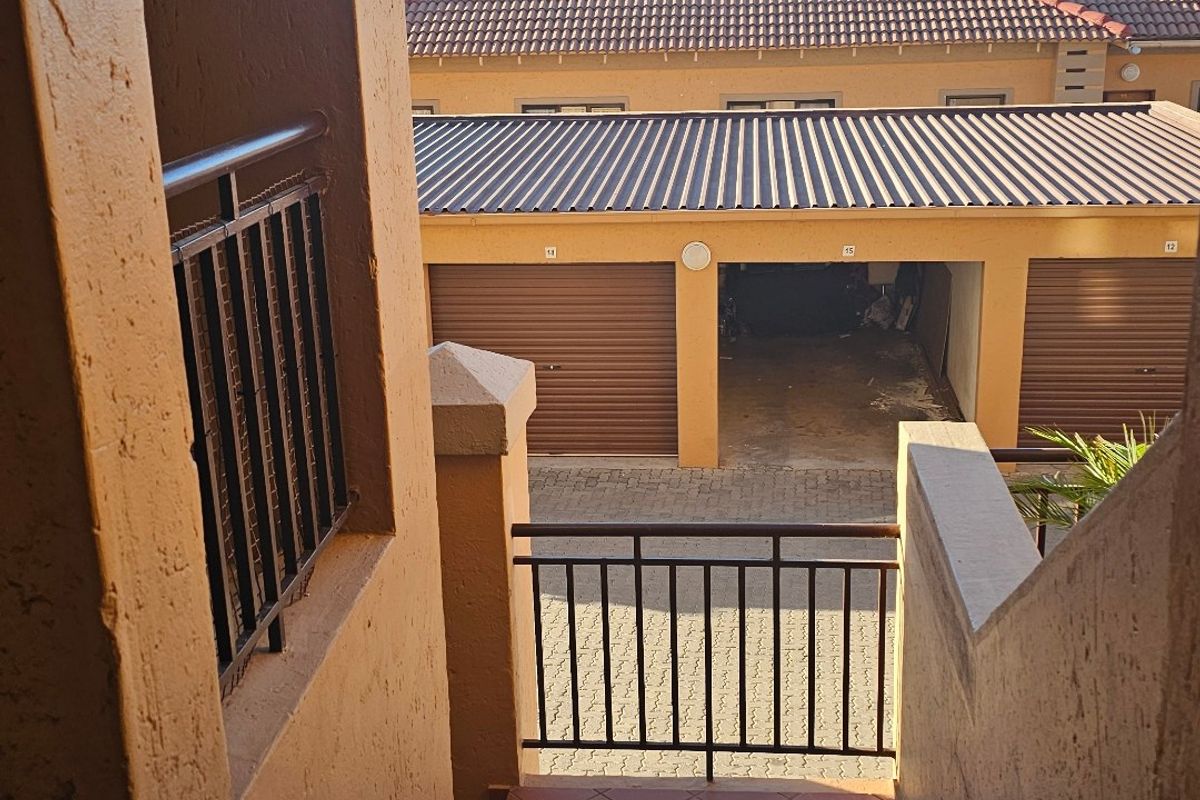 Exterior view from a tiled staircase overlooking a residential complex with a garage block and paved driveway.