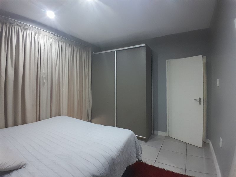 A bedroom featuring tiled flooring, recessed downlighting, and a built-in wardrobe with sliding doors.