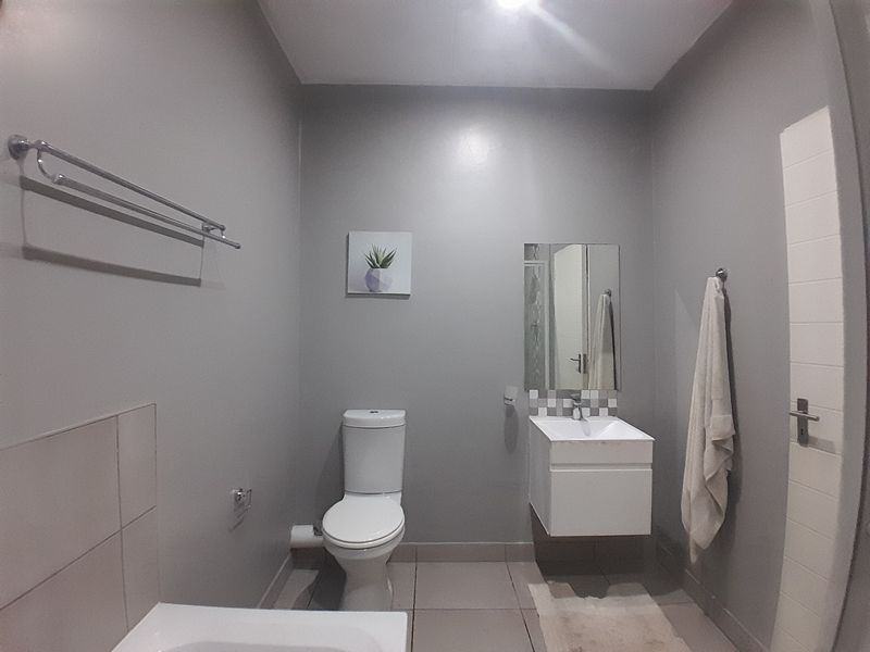 A clean and functional bathroom featuring a wall-mounted vanity, modern toilet, and neutral grey wall finishes.