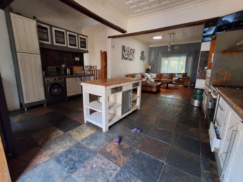 Spacious open-plan kitchen and living area featuring rustic slate tile flooring, pressed metal ceilings, and exposed timber beams with a central kitchen island.