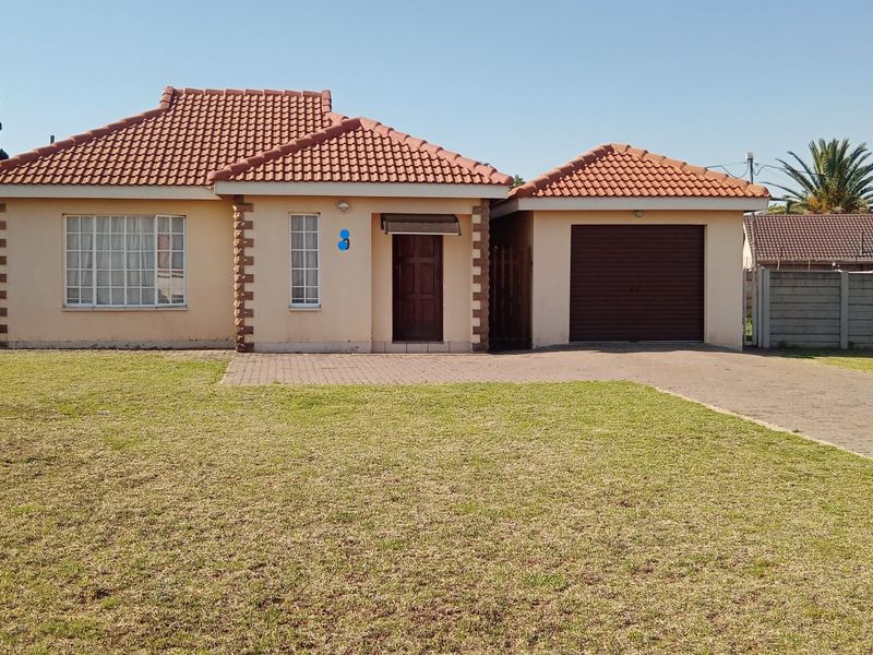 Front elevation of a single-story townhouse featuring a tiled roof, brick driveway, and an attached single garage set on a spacious lawn.
