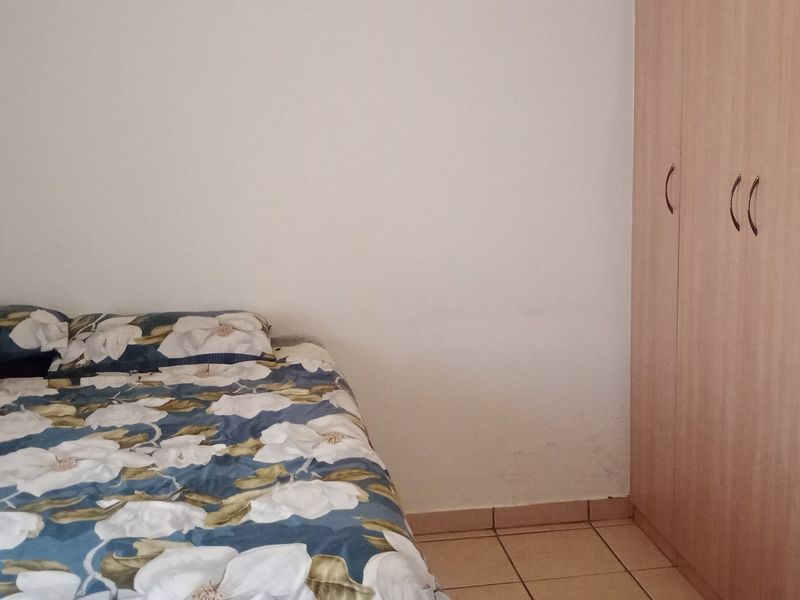 A bedroom featuring tiled flooring and a built-in wooden wardrobe.
