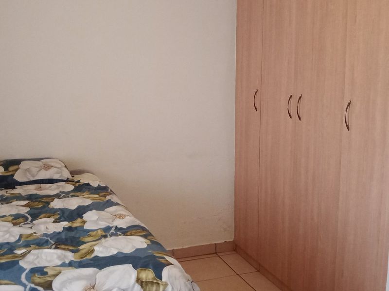 A bedroom featuring light wood-finish built-in wardrobes and tiled flooring.