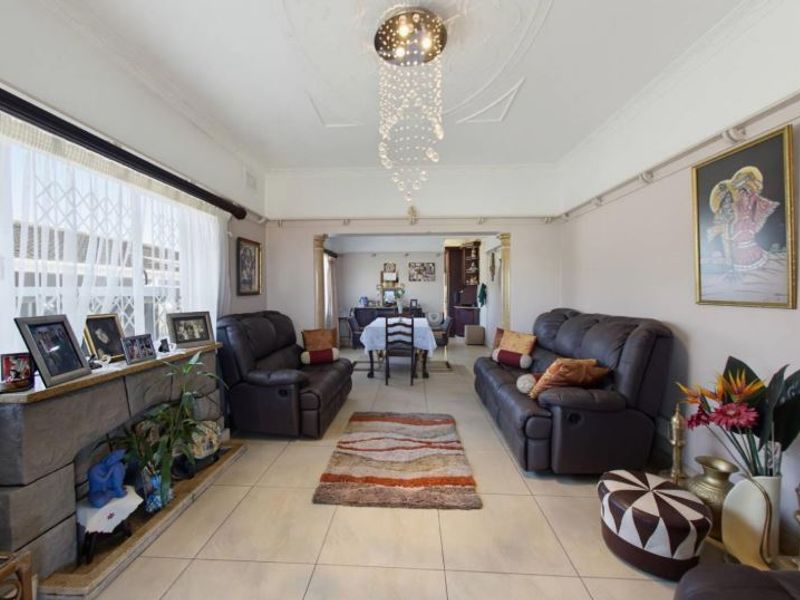 Open plan living and dining area featuring tiled flooring, a decorative ceiling rose, and a stone fireplace surround.