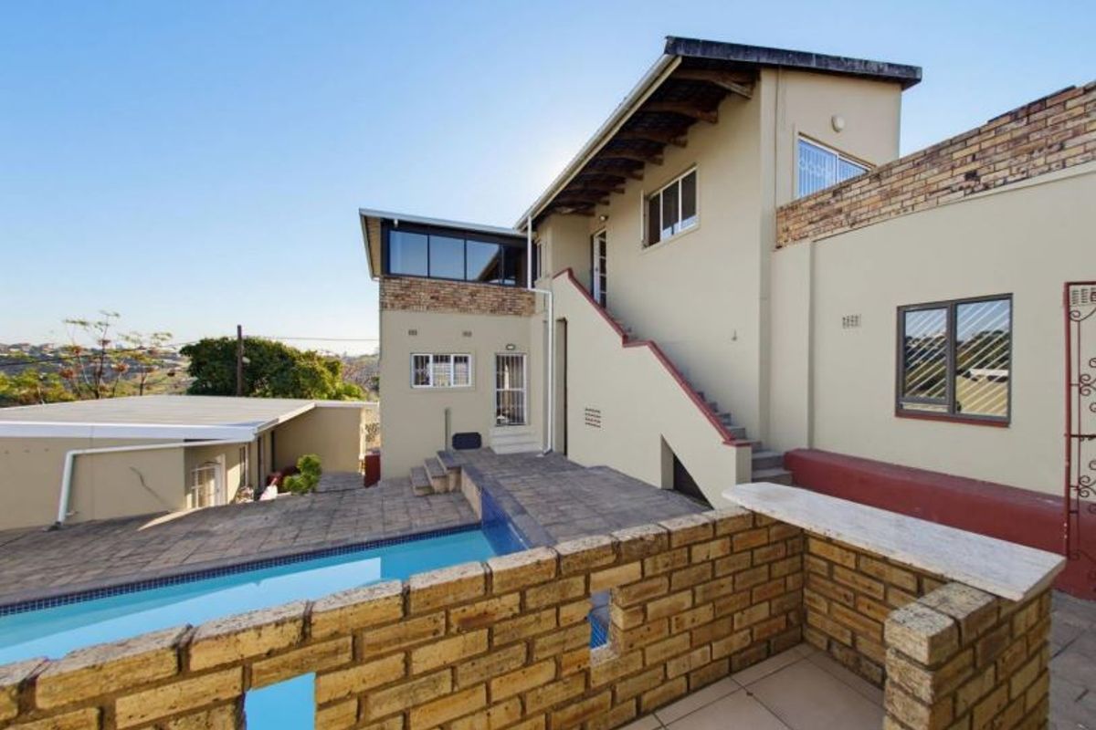 Rear exterior view featuring a swimming pool, paved patio area, and an external staircase leading to the upper level of the house.