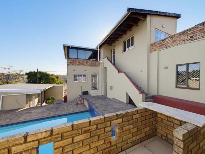 Rear exterior view featuring a swimming pool, paved patio area, and an external staircase leading to the upper level of the house.