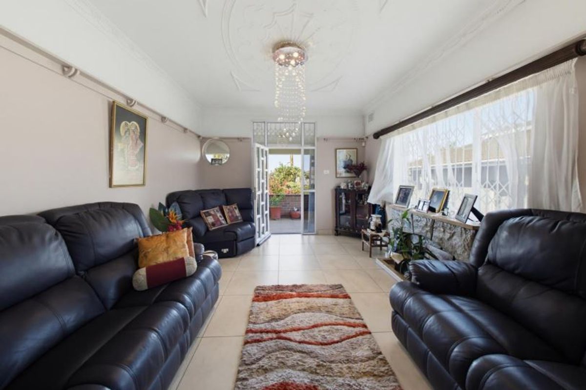 A living room featuring tiled flooring, an ornate ceiling rose, and a stone fireplace surround, with direct access to an outdoor patio area.