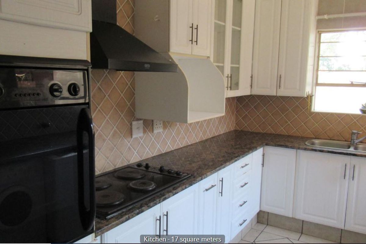 Functional kitchen featuring white cabinetry, dark laminate countertops, built-in oven, electric hob, extractor fan, and a double sink with tiled backsplash.