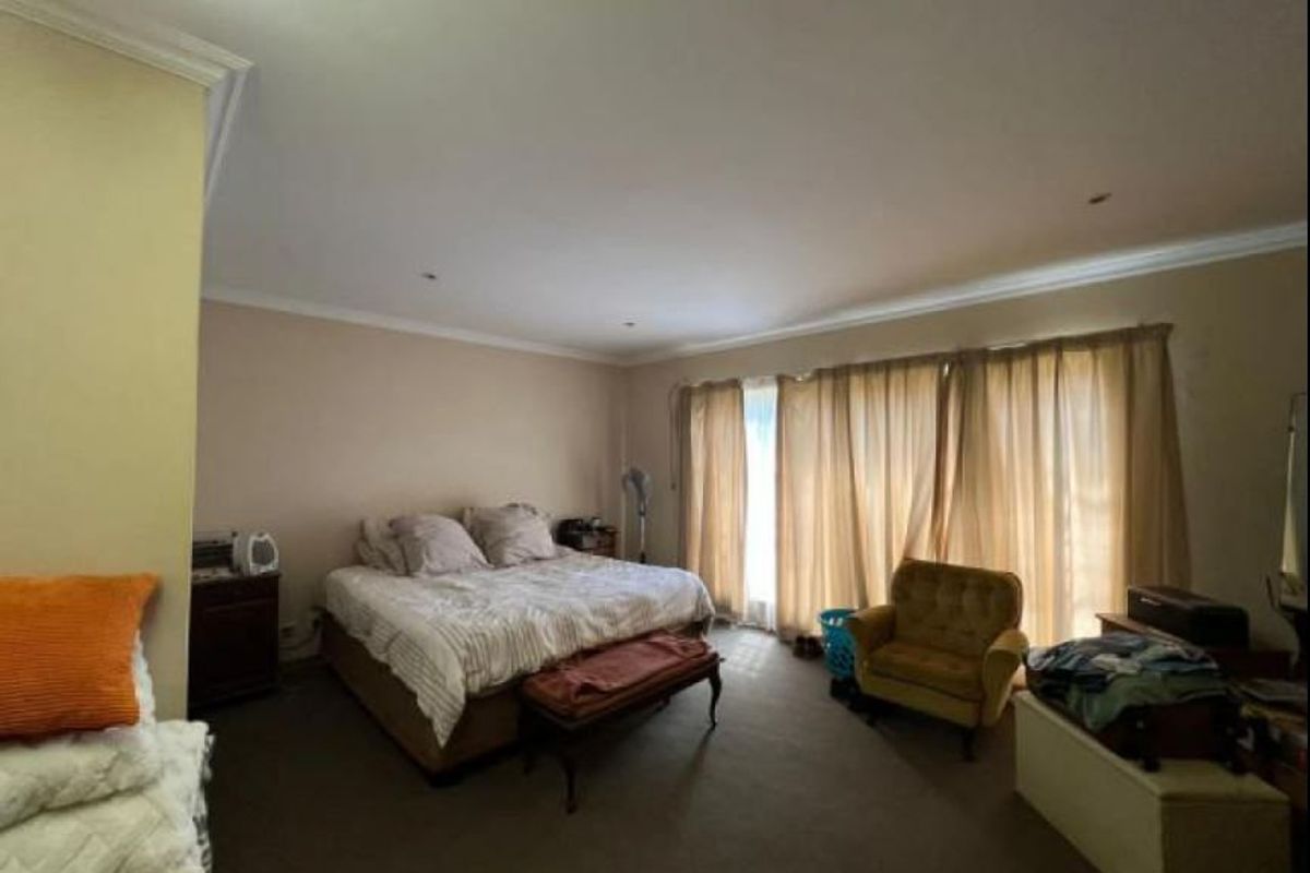 Spacious main bedroom featuring neutral wall tones, recessed downlighting, and large sliding glass doors providing natural light.