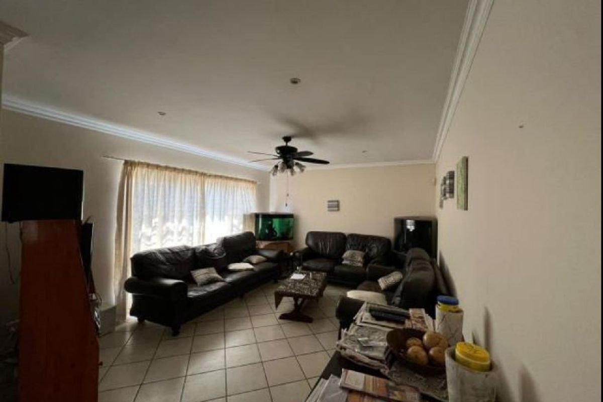 Spacious living room featuring tiled flooring, recessed lighting, and a ceiling fan, offering a comfortable area for relaxation.