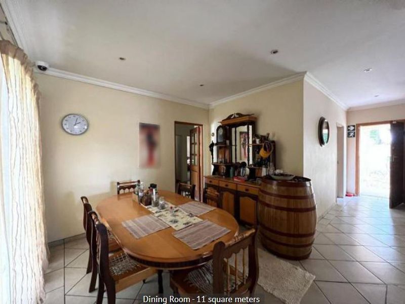A functional dining room featuring tiled flooring, recessed ceiling lighting, and decorative coving, providing a practical space for family meals.