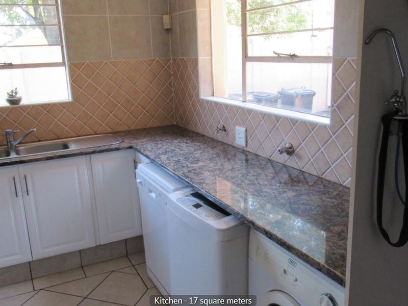 Functional kitchen featuring granite countertops, tiled backsplash, double bowl sink, and integrated plumbing for laundry appliances.