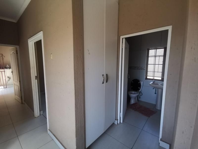 A functional hallway featuring built-in storage cupboards and direct access to an adjacent bathroom with a pedestal basin and toilet.