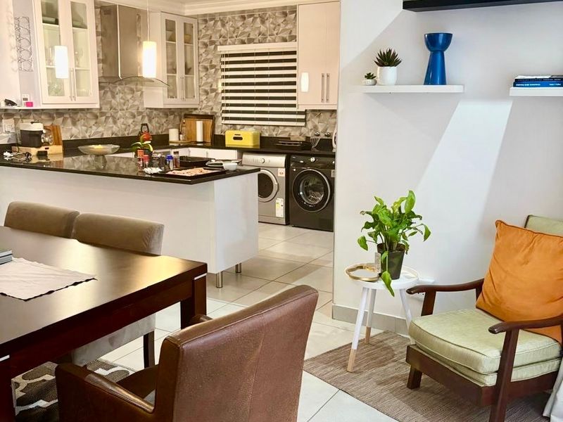Open plan living and dining area featuring a modern kitchen with granite countertops, sleek cabinetry, and integrated laundry appliances.