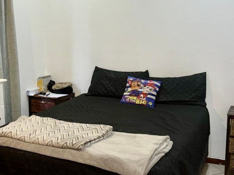 A functional bedroom featuring tiled flooring, recessed ceiling lighting, and decorative coving, providing a neutral base for personalization.