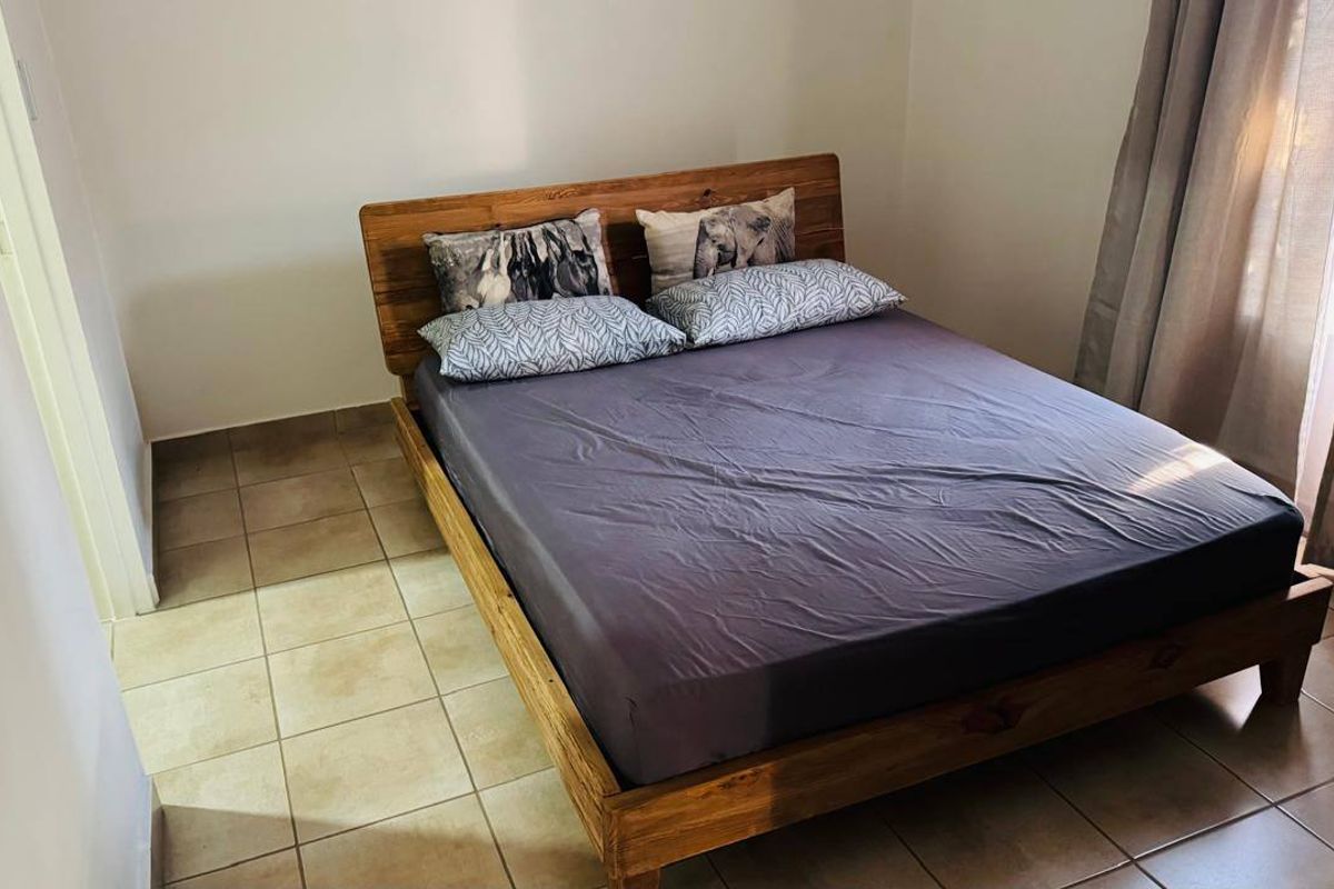 A functional bedroom featuring neutral tiled flooring and window treatments, providing a clean and simple space.