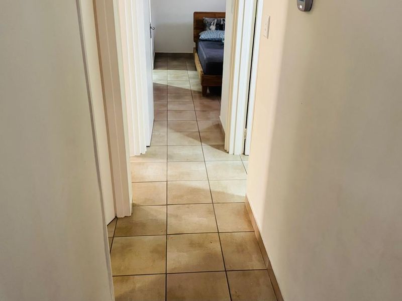 A functional hallway featuring neutral tiled flooring and access to adjacent rooms, providing a clean and simple transition space within the townhouse.
