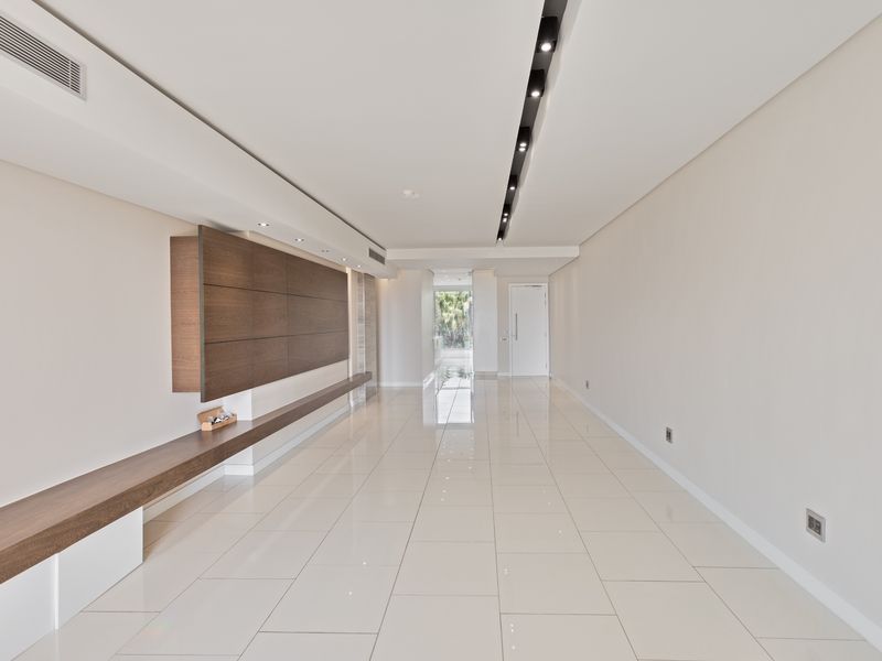 Spacious, modern living area featuring polished porcelain floor tiles, recessed ceiling lighting, ducted air conditioning, and sleek built-in timber cabinetry.