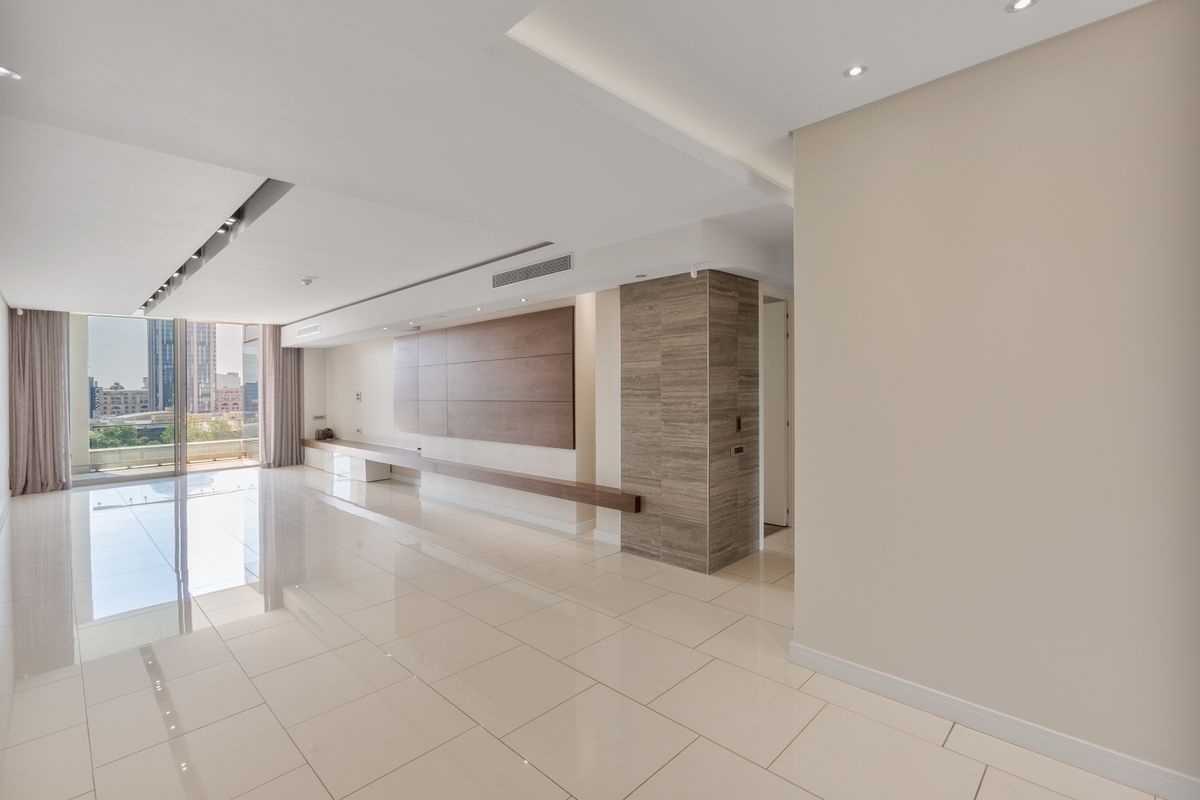 Spacious, modern living area featuring high-gloss tile flooring, recessed lighting, ducted air conditioning, and elegant wood and stone feature wall elements.
