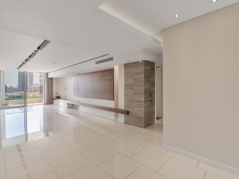 Spacious, modern living area featuring high-gloss tile flooring, recessed lighting, ducted air conditioning, and elegant wood and stone feature wall elements.