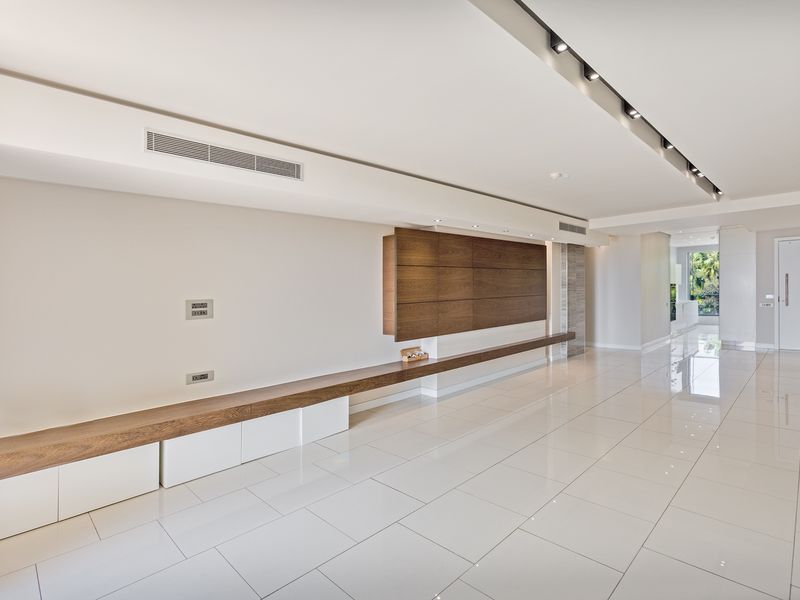 Spacious, modern living area featuring high-gloss tiled floors, custom built-in wooden cabinetry, and integrated recessed lighting with ducted air conditioning.