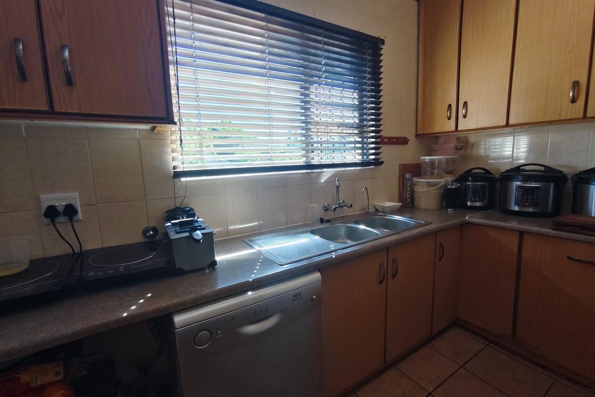 A functional kitchen featuring laminate cabinetry, tiled backsplash, double bowl stainless steel sink, and tiled flooring with ample counter space.