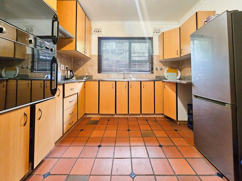 A functional kitchen featuring built-in cabinetry, granite countertops, a stainless steel sink, and a built-in oven with an extractor fan.
