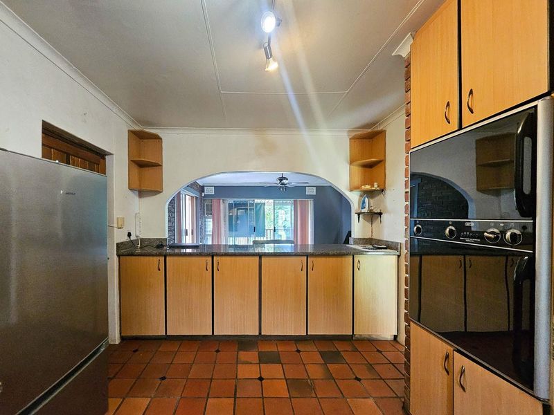 A functional kitchen featuring built-in cabinetry, granite countertops, and a built-in oven, with an open archway connecting to the adjacent living space.