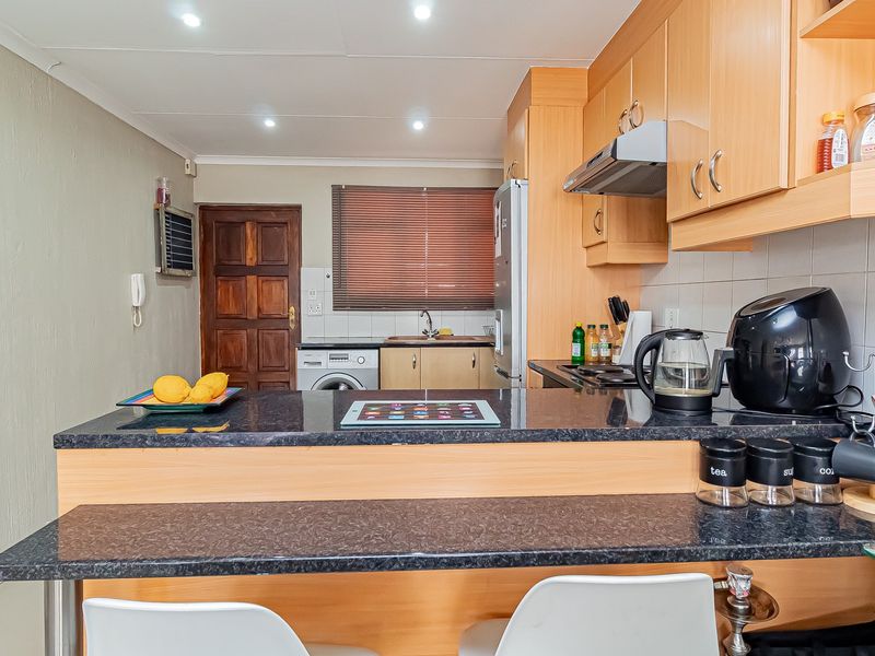 A functional kitchen featuring laminate cabinetry, granite countertops, a breakfast bar, and integrated appliances, offering a practical layout for daily use.