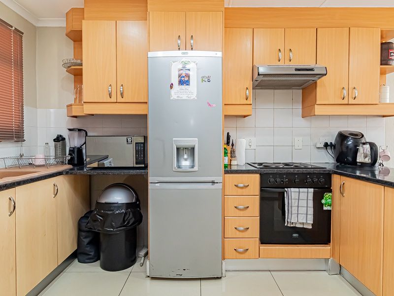 A functional kitchen featuring light wood-tone cabinetry, a built-in oven with hob, extractor fan, and tiled backsplash, offering a practical layout for daily use.