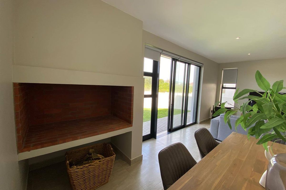 A bright living area featuring a built-in brick fireplace, tiled flooring, and large sliding glass doors providing direct access to the outdoor space.