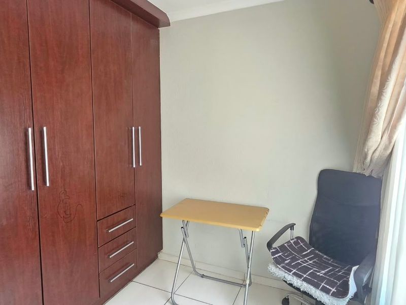 A bedroom featuring a large built-in wooden wardrobe and tiled flooring, providing functional storage space.