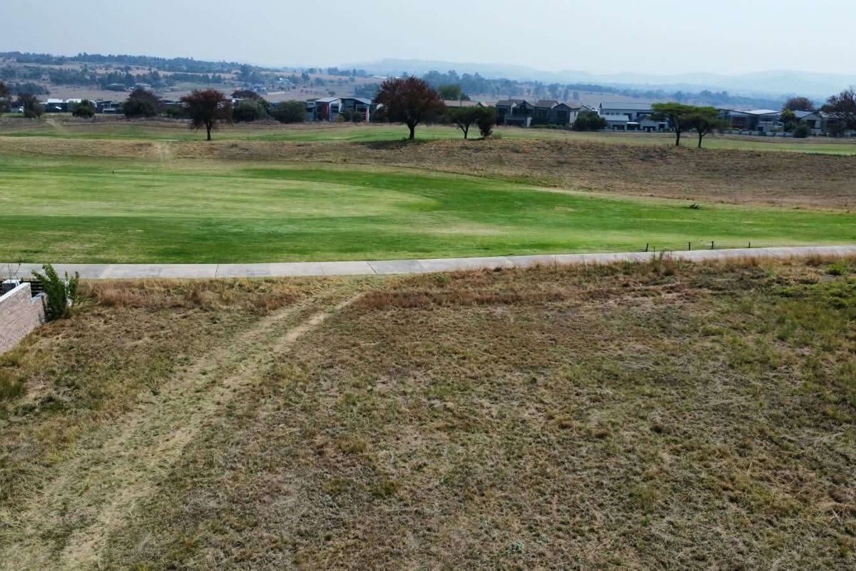 Aerial view of a vacant residential plot overlooking a golf course and surrounding estate landscape.