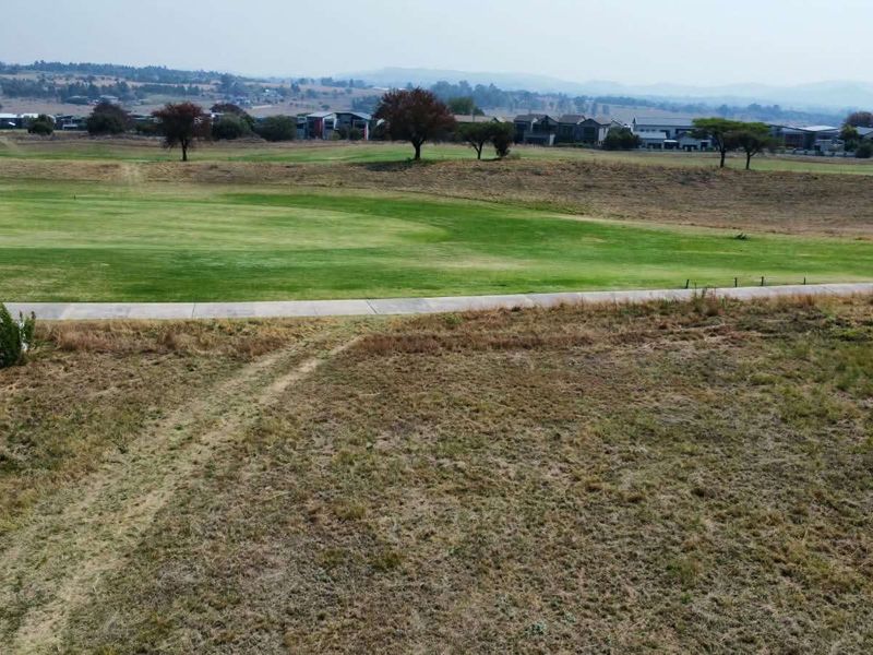 Aerial view of a vacant residential plot overlooking a golf course and surrounding estate landscape.
